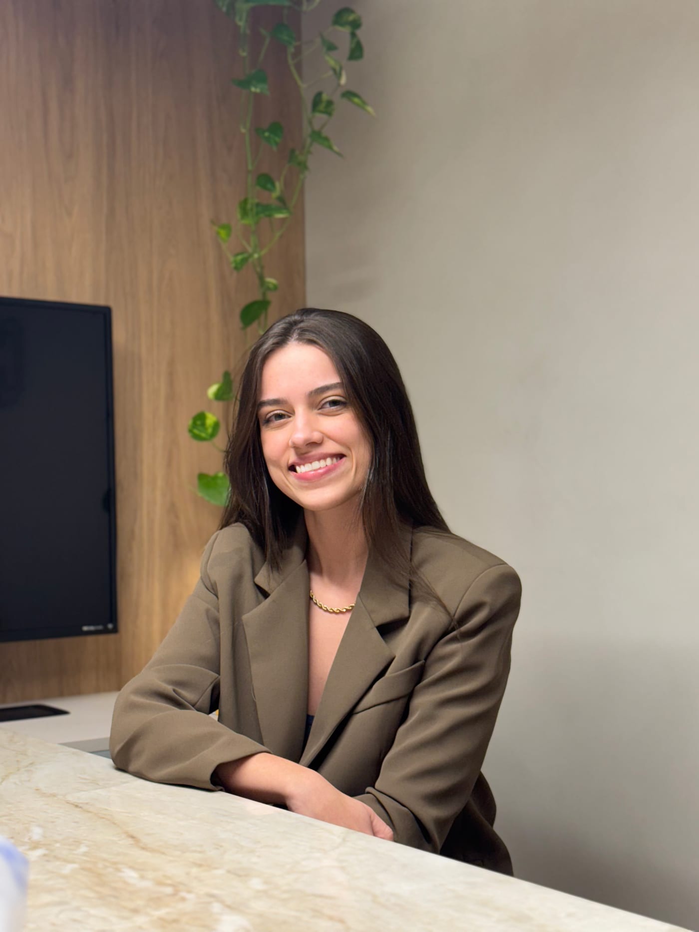 Retrato da arquiteta responsável pela Arquitetura Clara, sorrindo em um ambiente com painel de madeira